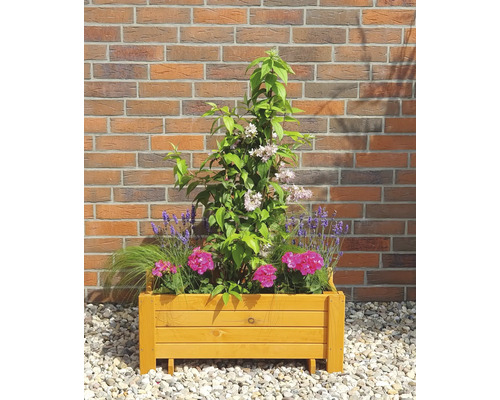 Holzblumenkasten bepflanzt mit Blumen und Pflanzen vor einer Ziegelmauer