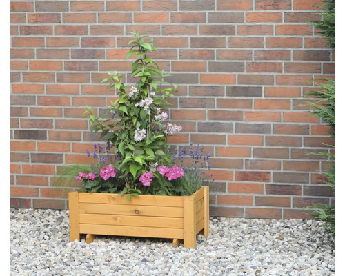 Holzpflanzkasten mit Blumen vor einer Backsteinmauer