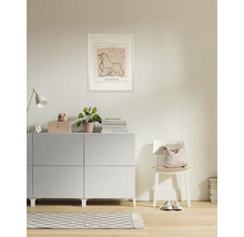 Wohnzimmer mit Kommode, Lampe, Zimmerpflanze, Bilderrahmen und Stuhl mit Rucksack