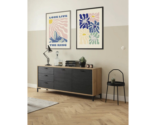 Wohnzimmer mit Sideboard, Lampe, Dekoration, Wandbildern und Beistelltisch.