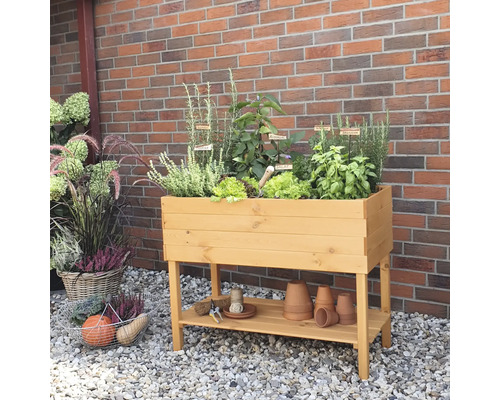 Hochbeet aus Holz mit Kräutern und Gemüse vor einer Backsteinmauer