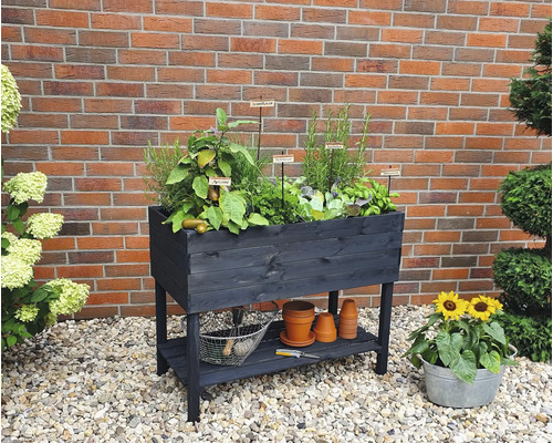 Hochbeet aus Holz mit Kräutern und Gemüse auf einer Terrasse mit Steinen