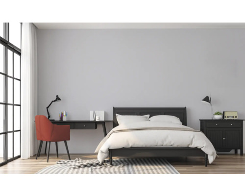 Schlafzimmer mit Bett, Schreibtisch und Stuhl in einem hellen Raum