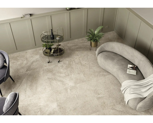 Heller Raum mit Bodenfliesen in Marmoroptik, Sofa, Barwagen und Zimmerpflanze.