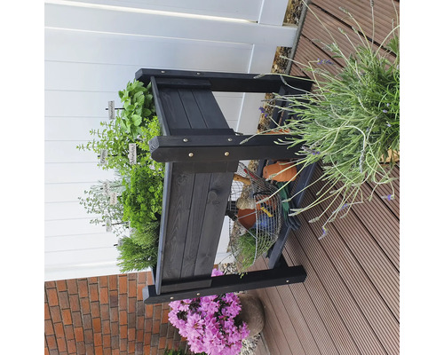 Schwarzes Kräuterregal aus Holz mit verschiedenen Kräutern und Gartenutensilien auf einer Terrasse