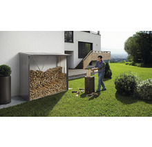 Holzlager mit Holz neben einem Mann, der Holz hackt, im Garten