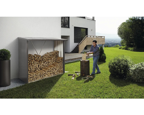 Überdachter Holzunterstand mit Holz neben einem Mann, der Holz spaltet