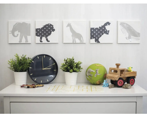 Dekoratives Kinderzimmer mit Tiermotiven, Uhr, Pflanzen und Spielzeug auf einem weißen Tisch