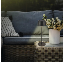 Dekorative Solarleuchte auf einem Tisch im Außenbereich neben einer Vase mit Blumen und einer Couch.