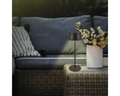 Dekorative Solarleuchte auf einem Tisch im Außenbereich neben einer Vase mit Blumen und einer Couch.
