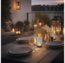 Abendliche Tischdekoration mit Geschirr, Gläsern und Laternen auf einer Terrasse