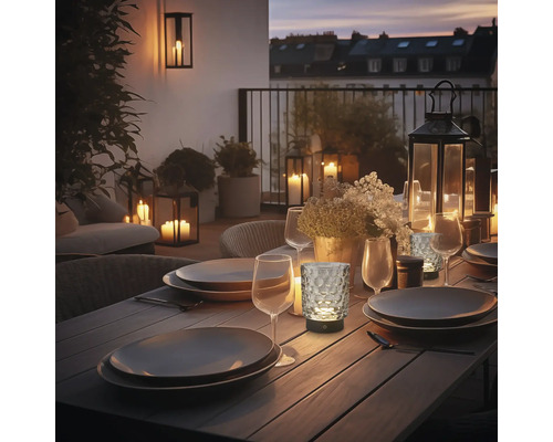 Abendliche Tischdekoration mit Geschirr, Gläsern und Laternen auf einer Terrasse