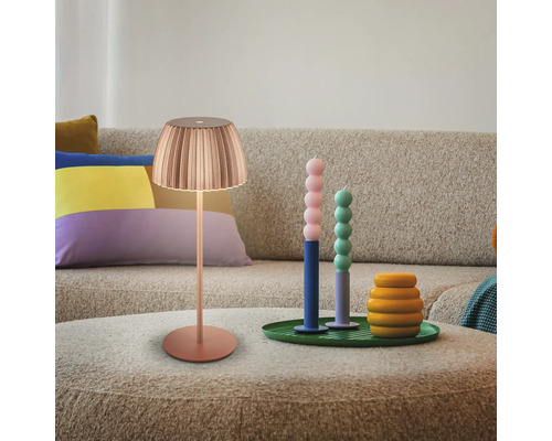 Szene mit Lampe, Kerzen und Dekorationsartikeln auf einem Tisch vor einem Sofa.