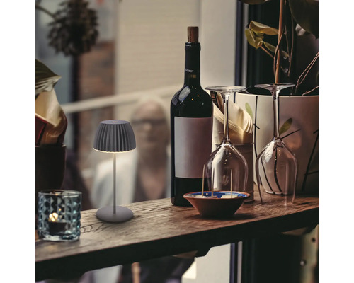 Dekorative Tischleuchte neben Weinflasche und Gläsern auf einem Regal