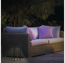 Gartenszene mit Rattan-Lounge-Sofa, Kissen und dekorativer Laterne für den Außenbereich