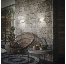 Außenbereich mit Rattan-Stuhl, Steintisch und Wandleuchten