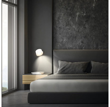Schlafzimmer mit Bett, Nachttisch und Wandleuchte