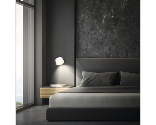 Schlafzimmer mit Bett, Nachttisch und Wandleuchte