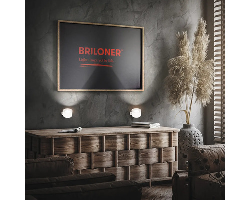 Wohnzimmer mit Kommode, Wandleuchten, Briloner Logo und Dekoration