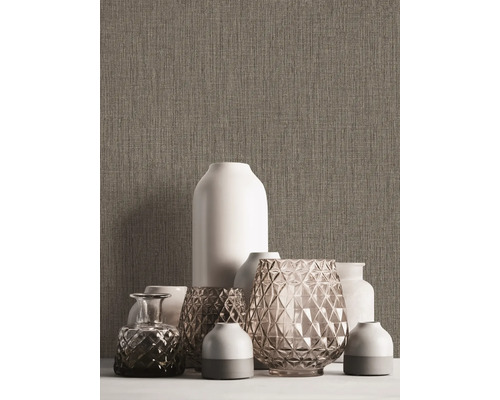 Verschiedene dekorative Vasen auf einem Tisch vor einer strukturierten Wand.