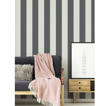 Szene mit gestreifter Tapete, Sofa mit Decke, Kissen und einem gerahmten London-Druck auf einem Nachttisch.