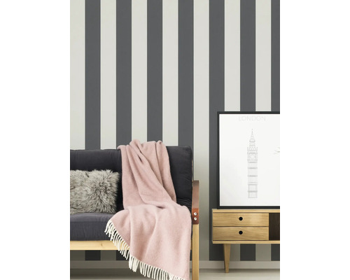 Szene mit gestreifter Tapete, Sofa mit Decke, Kissen und einem gerahmten London-Druck auf einem Nachttisch.