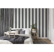 Schlafzimmer mit Bett, Nachttisch und gestreifter Tapete