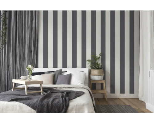 Schlafzimmer mit Bett, Nachttisch und gestreifter Tapete