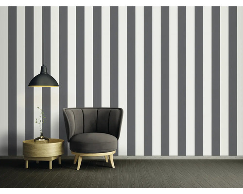 Raumansicht mit gestreifter Tapete in Grau und Weiß, Sessel, Beistelltisch und Hängelampe