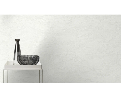 Dekorative Vase und Schale auf einem kleinen Tisch vor einer Wand mit Putzstruktur.