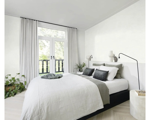 Helles Schlafzimmer mit Bett, Nachttisch, Lampe, Vorhängen und Zimmerpflanze