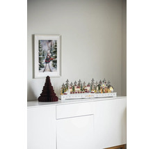 Dekorative Weihnachtsszene mit beleuchteter Winterlandschaft, Papierbaum und Zugbild auf einem weißen Schrank