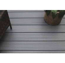 Nahaufnahme einer Terrasse mit Holzdielen, einem Rattansessel und einem Blumentopf.