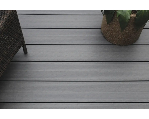 Nahaufnahme einer Terrasse mit Holzdielen, einem Rattansessel und einem Blumentopf.