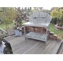 Gartenszene mit einem grauen Pflanztisch mit Metalloberfläche und Holzregal im Freien