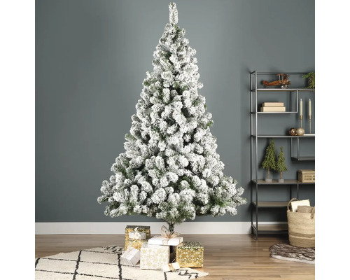 Geschmückter, beschneiter Weihnachtsbaum mit Geschenken im Wohnzimmer.