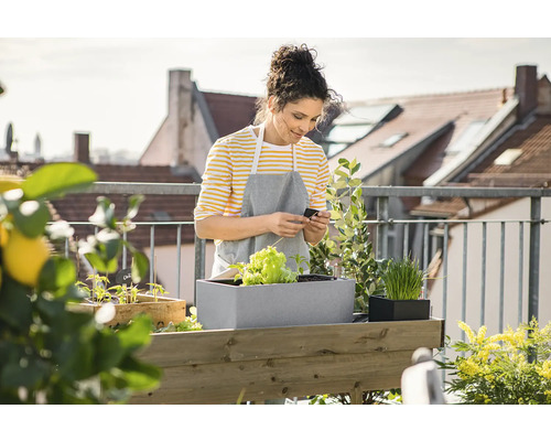 Frau auf einem Balkon mit Hochbeet und Pflanzen