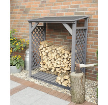 Holzlager mit Holz, Axt und Hackklotz vor einer Ziegelmauer