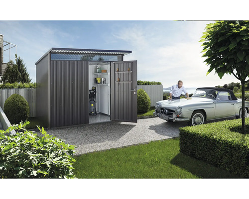 Metall Gerätehaus mit geöffneten Türen, Regalen, Hochdruckreiniger und einem Mann, der ein Auto putzt