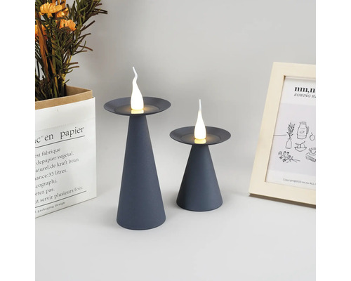 Zwei graue LED-Kerzenleuchten auf einem Tisch, dekorative Elemente im Hintergrund