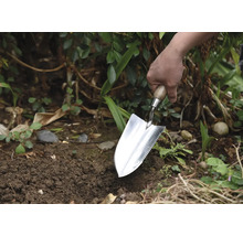 Gärtner pflanzt mit einer Pflanzkelle im Garten.