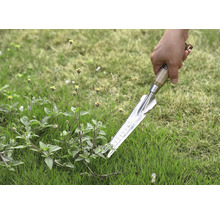 Nahaufnahme einer Hand, die einen Unkrautstecher im Gras hält