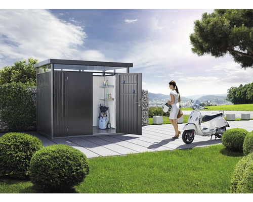 Moderner Geräteschrank aus Metall mit Regalen, Hochdruckreiniger und einer Frau mit Roller im Garten.