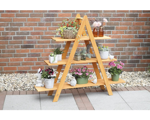 Dekoleiter „Maxi“ aus Holz 137 x 31 x 120 cm honigfarben Holzpflanzentreppe mit drei Ebenen und verschiedenen Topfpflanzen vor einer Backsteinmauer