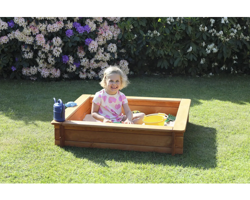 Mädchen spielt in einem Sandkasten mit Sandspielzeug im Garten