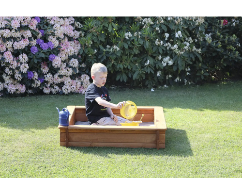 Junge spielt mit Sandspielzeug in einem Sandkasten im Garten.
