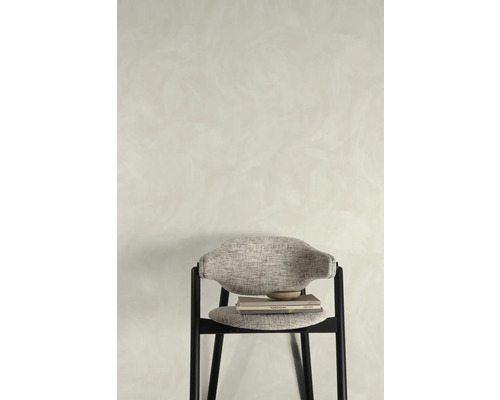 Stuhl mit Textilbezug, Büchern und Schale vor einer Wand