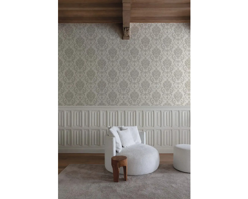 Wohnraum mit gemusterter Tapete, gepolstertem Sessel und Holzschemel