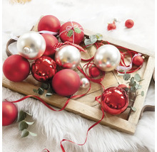 Dekorative Weihnachtskugeln in Rot und Silber auf einem Holztablett mit Schleifenband und Eukalyptuszweigen.