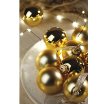 Goldene Weihnachtskugeln auf einem Teller mit Lichterkette.